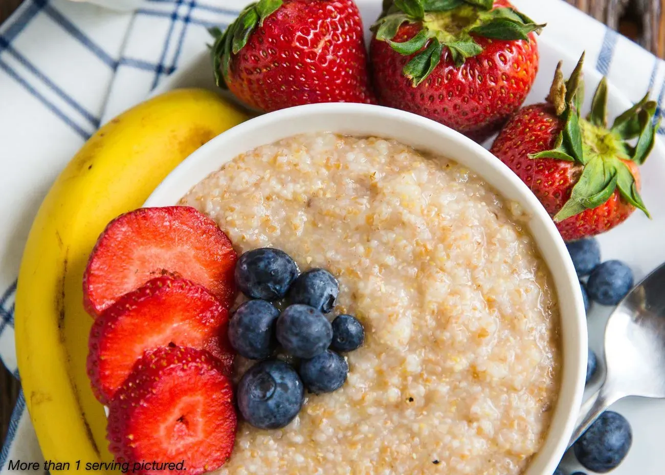 Prepared bowl of Amber Grains breakfast cereal with fresh strawberries, blueberries, and a banana.