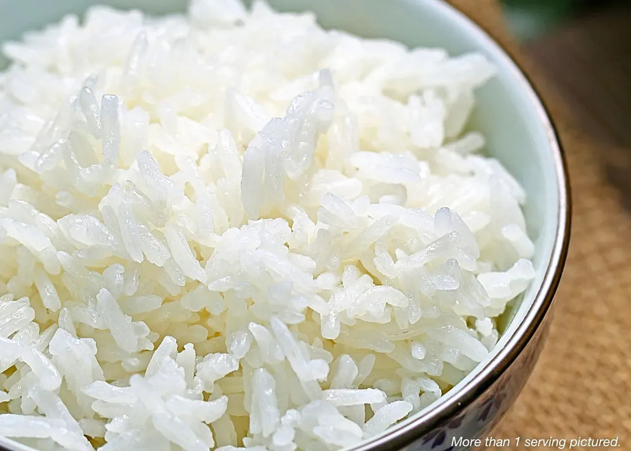 A close-up view of a ceramic bowl filled with fluffy, steamed white rice.