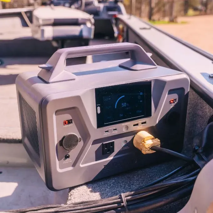 A practical outdoor shot focusing on a gray 4Patriots solar generator sitting inside the textured interior of an open boat.