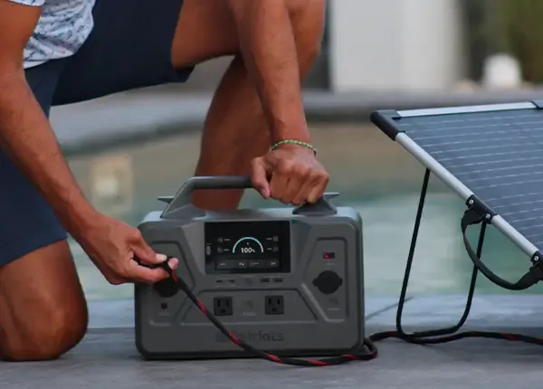 A man outdoors plugging in the 4Patriots 100W laminate solar panel into the Patriot Power Generator 1200.