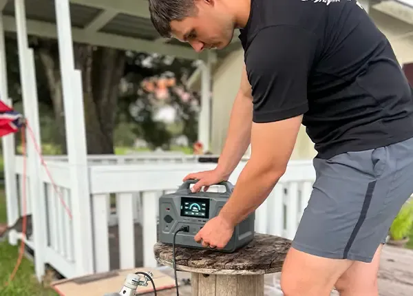 A man transports a 4Patriots portable solar generator at a campsite, highlighting its use for providing power while camping off-grid.