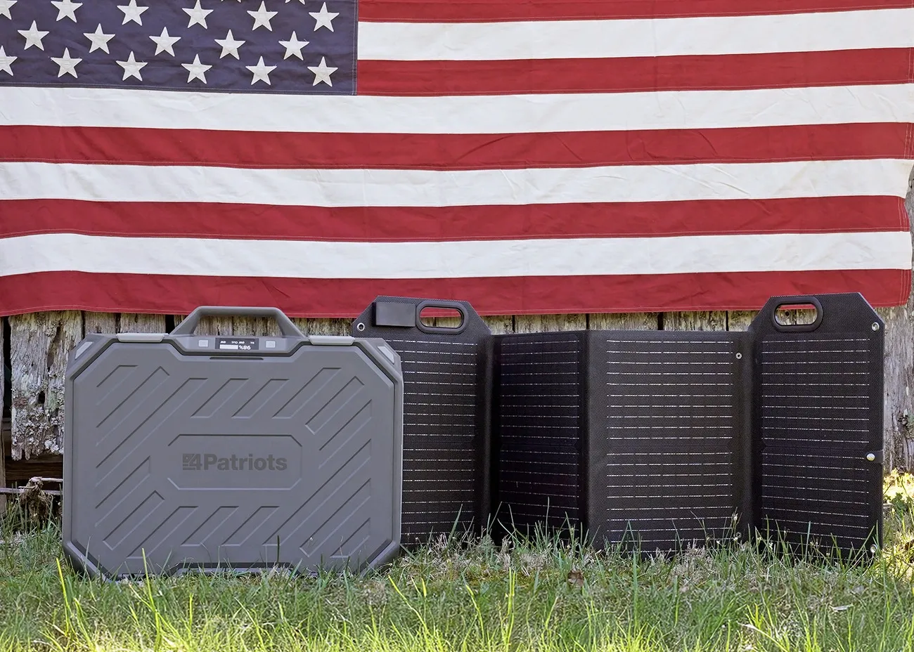Patriot Power Generator AlphaCase Elite and unfolded 60-watt solar panel set on grass in front of an American flag.