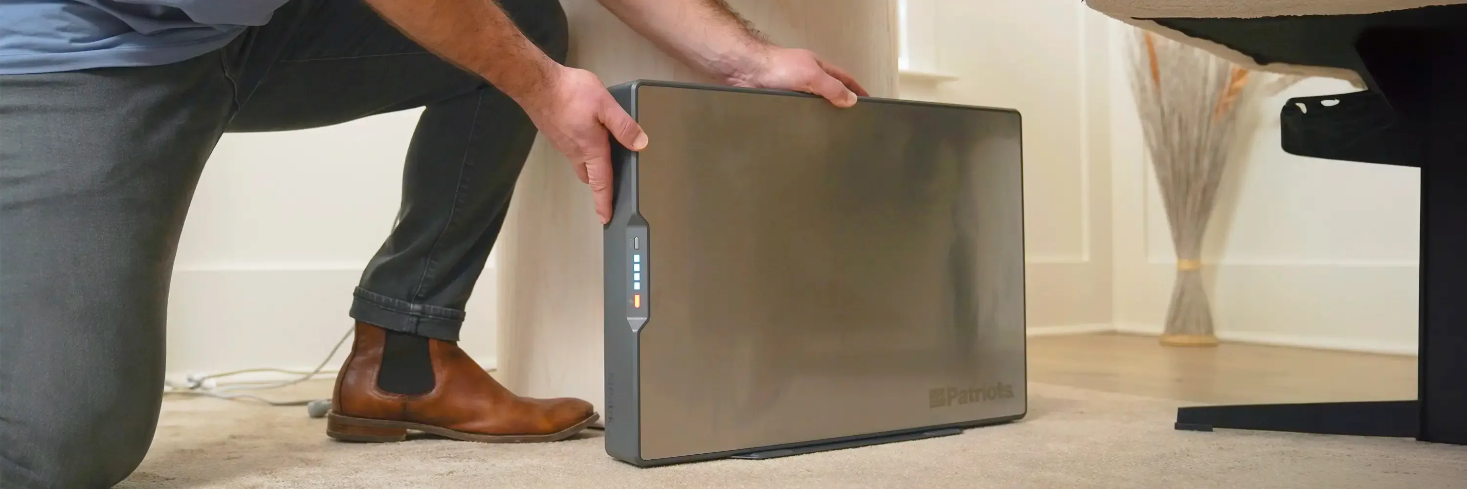 A woman sets up portable solar panels on a grassy clearing while a man sits nearby on a wooden bench holding a tablet. In the foreground, a 4Patriots solar generator is connected to the panels, with autumn trees in the background.