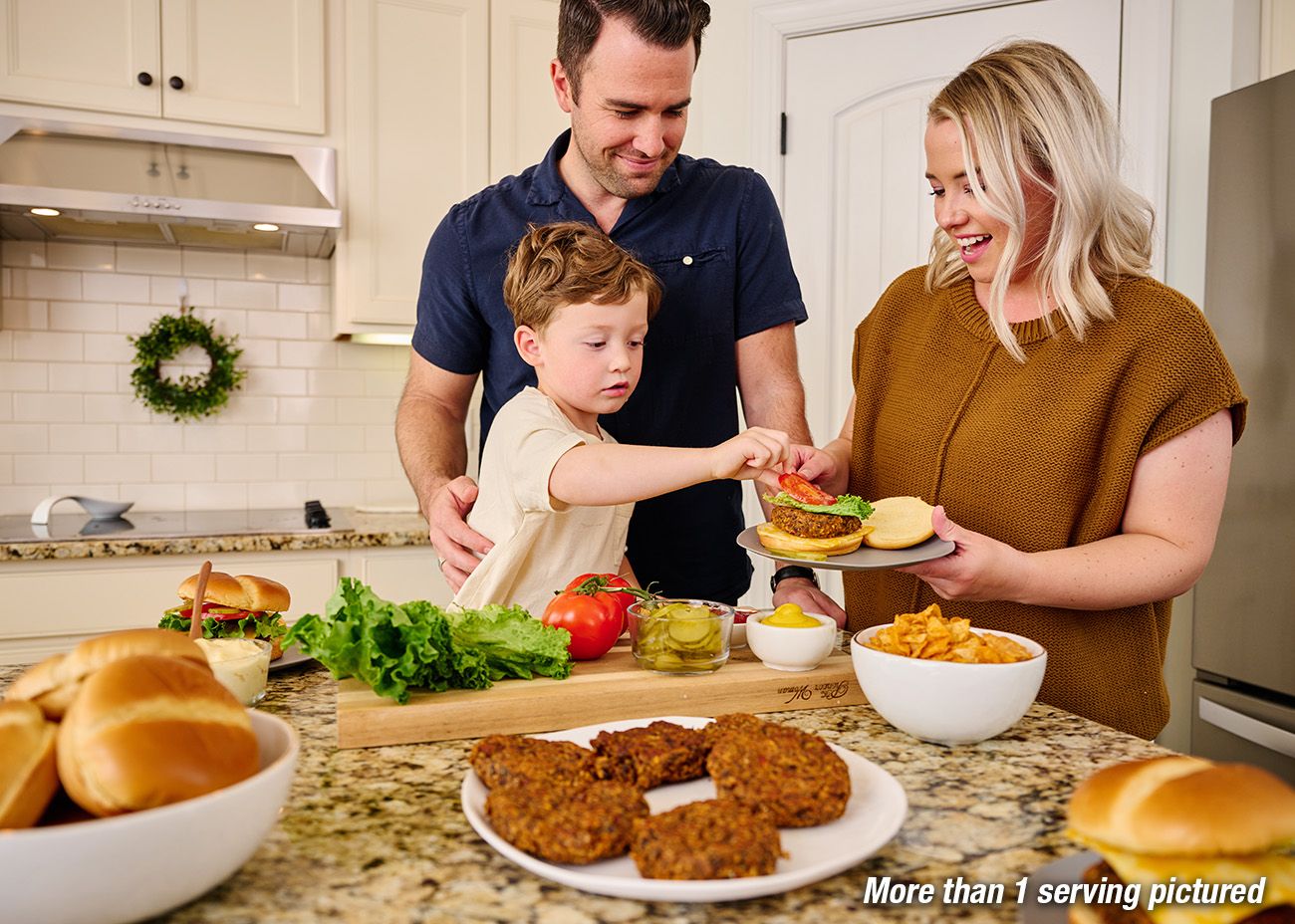 Family preparing black bean burgers together in the kitchen. Ingredients to make the burgers are presented on the counter. More than 1 serving is pictured.