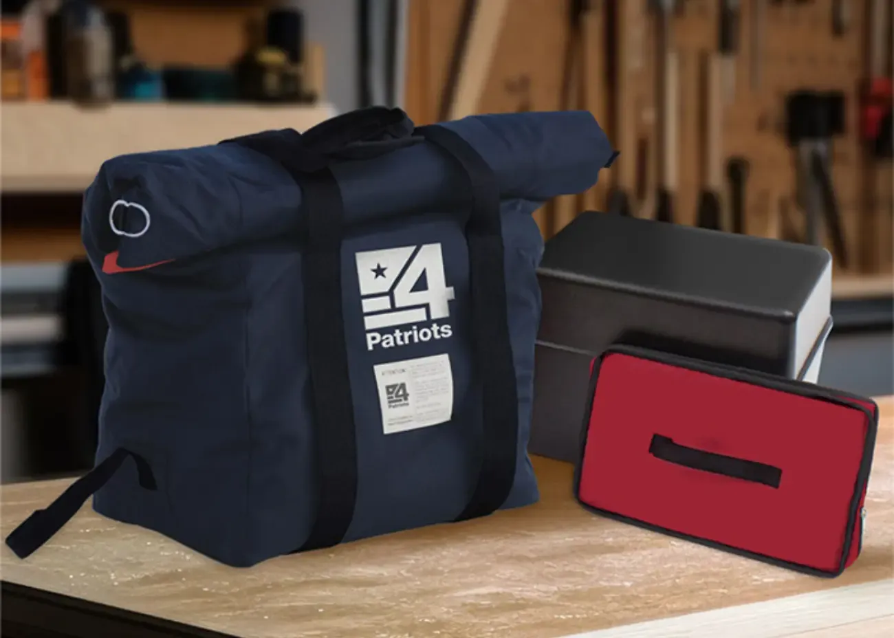 4Patriots EMP Protection Bag A 4Patriots EMP bag designed for solar generator protection sits on a workbench in a garage, alongside a black Faraday container and a compact red zippered pouch. The heavy-duty navy blue bag features reinforced black straps and bold 4Patriots branding, emphasizing durable, off-grid power security.