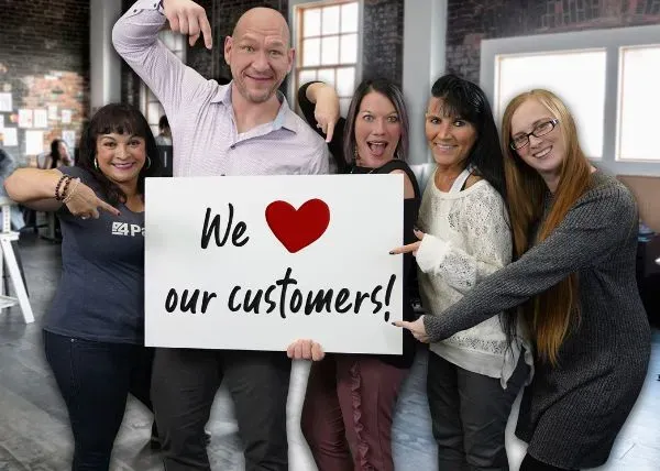 4Patriots Customer Service Team Five people in an office setting holding a sign that says, "We ❤️ our customers!"