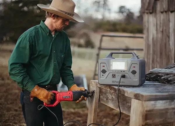 A man outdoors using the 4Patriots Patriot Power Generator 1200 to power a wood working power tool.