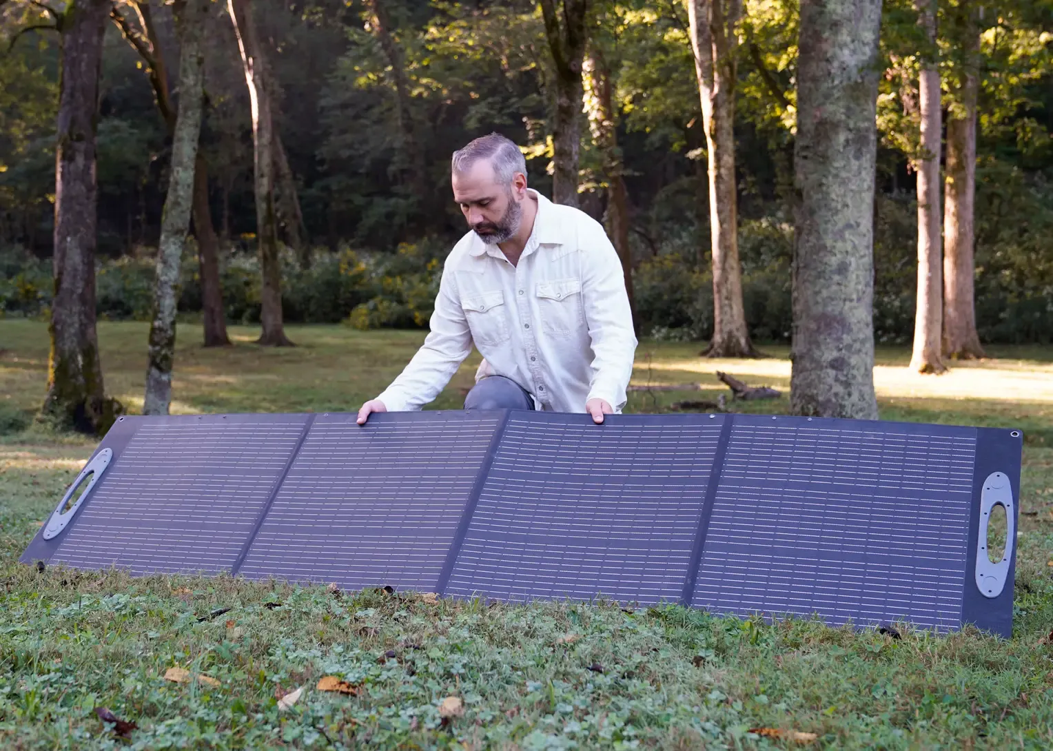 Patriot Power Solar Generator 2500X off grid A retro camper van with a wooden pop-top roof is parked on grassy land with its side door open. In front of it, a portable solar panel and 4Patriots power station are set up, showcasing off-grid energy for van life and outdoor living.